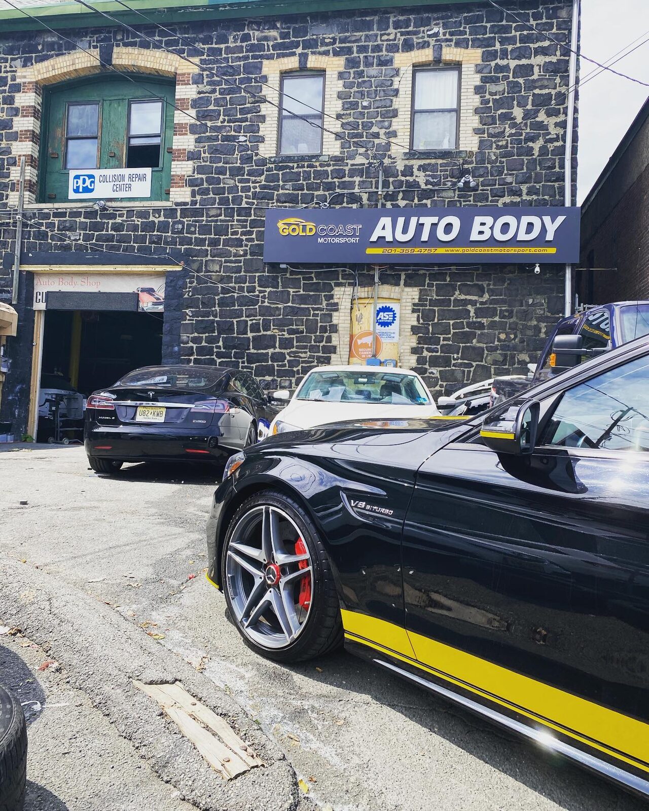 Side view of the same black Mercedes-AMG C63 showing the yellow stripe running along the rocker panel.